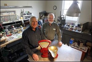 David Hankenof, left, and Peter Kern, right,  former Toledo Scale employees, stand with their refurbished vintage scales.