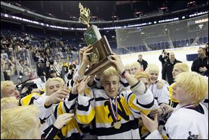 Northview's Dalton Carter holds the state hockey championship trophy as teammates reach to get a hand on  it. The Wildcats finished the season 31-1-3.