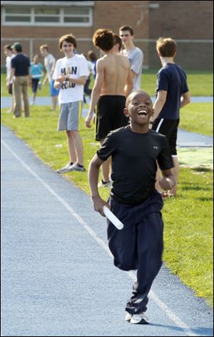 Sixth grader Christian Harton, 11, an enthusiastic runner who's eager for Toledo's Glass City Marathon on April 22, grins as he races by.