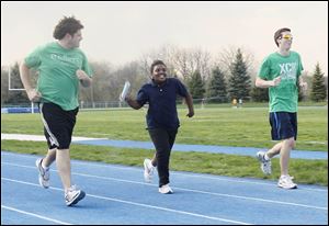 Brielle Rison, 9, says she's never run a mile, but she's finishing her laps and getting encouraging words from mentors Pat McCarty, left, and Anthony Maraldo, right, as she crosses the finish line. 