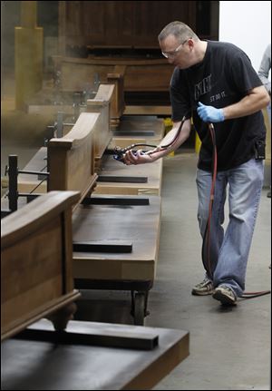 Mark Bollinger sprays a finish on some wooden footboards for beds inside a spray booth at the Lincolnton Furniture Company in Lincolnton, N.C. 