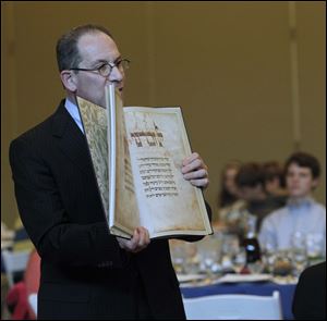 Rabbi Sam Weinstein shows an ornate haggadah, or Seder guide, at the interfaith Seder.