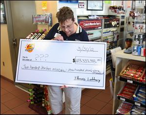 Red Bud, Illinois Moto Mart store manager Denise Metzger looks at an oversized check given to her by lottery officials Saturday morning. They visited the convenience store in this town of about 3,700 residents to verify that her store had indeed sold one of the three winning Mega Millions lottery tickets.