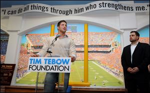 Tim Tebow speaks as his foundation opens the first Timmy's Playroom, for children battling life-threatening illness, in Jacksonville, Fla. Erik Dallenback, right, is the foundation's executive director.