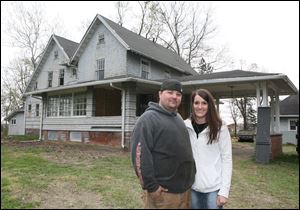 Jason and Kelly Amstutz in front of the foreclosed home they recently bought in Oregon, Ohio.