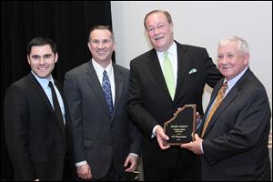 Wood County commissioners, from left, Joel Kuhlman, Tim Brown, and Jim Carter, far right, honor Clarence Gooden, third from left, executive vice president of CSX Transportation, with the Corporate Citizen of the Year Award.