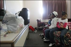 From left, Asia, Tih'Ron, and Aaliyah Hartfield watch TV at the Red Roof Inn in Maumee as their sister, Shytasia Fisher, back left, sits behind the TV. The family lost everything in the Hidden Cedars complex fire on March 25.