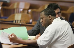 Anthony Belton looks through papers as a defense witness offers testimony. Behind him is defense attorney Neil McElroy. Belton faces a sentence of life in prison or death in the 2008 shooting death of Matthew Dugan, a clerk at a former BP gas station.