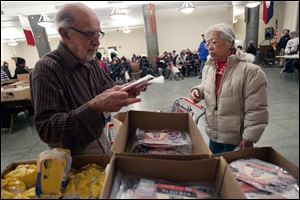Volunteer Paul Farris of Boston distributes hams in the Franciscan Food Center. The Traditional Easter centerpiece has risen in price.