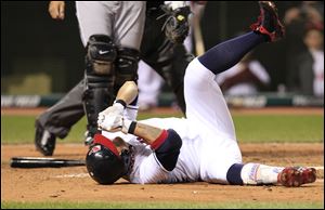 Cleveland Indians' Shin-Soo Choo rolls on the ground after getting hit by a pitch in the left hand in the sixth inning in a baseball game against the Chicago White Sox in Cleveland.