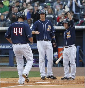 Mud Hens player Brad Eldred (44) is greeted at the plate by teammates Ryan Strieby (34) and Matt Young (13) after hitting a two-run homer off of Louisville Bats pitcher Sean Gallagher during the second inning.