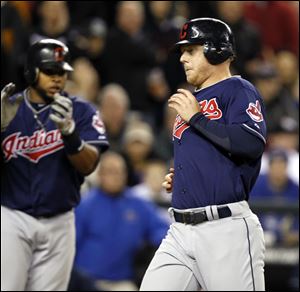 Cleveland Indians' Carlos Santana, left, applauds as Aaron Cunningham crosses the plate after the pair scored against the Seattle Mariners in the ninth inning Thursday.