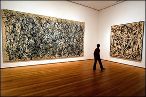 A visitor strolls by canvasses by Abstract Expressionist Jackson Pollock at the Museum of Modern Art in New York.