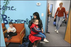Victoria Bernal and sons Justice, 5, in her lap, and Jace, 2, wait their turn at the Providence Center food pantry in South Toledo. They get by on child support, $328 a month in food stamps, and the occasional odd job, Ms. Bernal said.
