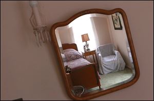 Guest bedroom furnishings are reflected in a mirror at the Winter House.