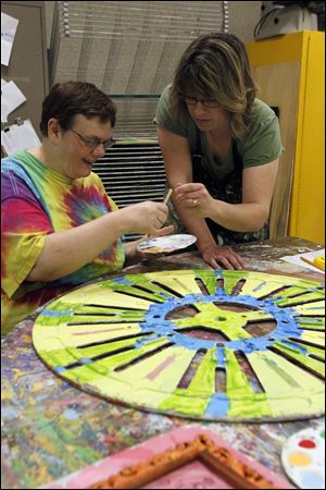 Cassandra Clark, left, paints a spool cap with help from Janice Cashel, an adult services provider with Blanchard Valley Center in Findlay.