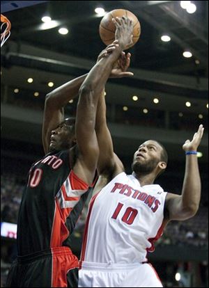 The Raptors' Solomon Alabi, left, is fouled by the Pistons' Greg Monroe, right, while going to the basket.
