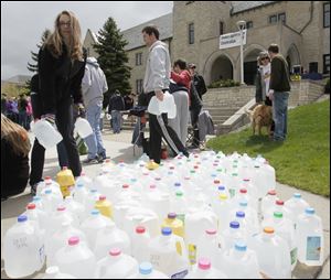Students Anna Konwinski, of Troy, Mich., and Brian Wellman of Coldwater, Ohio, pick up gallon water jugs for the march around the University of Toledo campus.