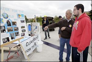 Paul Flickinger of Kalamazoo, Mich., left, speaks with UT student Chris Etzinger of Fostoria about the mission of Clean Water for the World and the water-purification system at left, which is destined for Haiti.  Saturday's event coincided with Earth Day weekend.