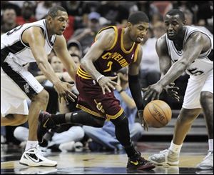 Cleveland's Kyrie Irving, center, fights for a loose ball against the  Spurs' Boris Diaw, left, and DeJuan Blair during the first half.