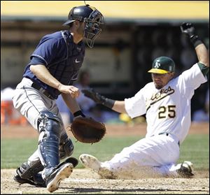 Oakland's Kila Ka'Aihue, right, slides to score behind Indians catcher Lou Marson during the fifth inning.