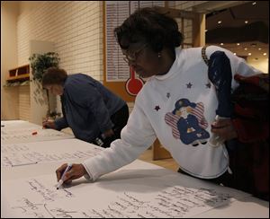 Pat Urbaniak of Holland, left, and Patricia Randolph of Toledo sign a letter to the Toledo Public Schools superintendent, Jerome Pecko, advocating use of a new program to handle student discipline.