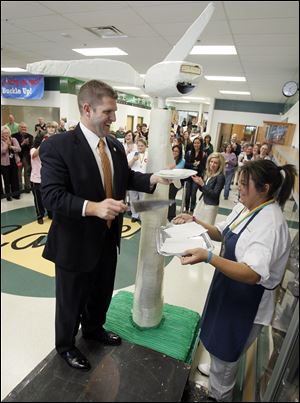 State Rep. Matt Szollosi serves up a piece of cake to Asha Henderson, Clay High School junior. The confection was modeled after the wind turbine and was 7 feet high.