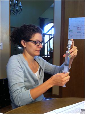 Megan Bringe prepares an infusion of the plasma that replaces the antibodies her system can't produce.