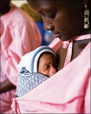 A mother carrys her unnamed twin baby, 11 days old, in the Kangaroo Care center at the Gabrielle Traoré Hospital in Bamako, Mali.