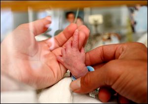 Adults hold the tiny hand of a premature baby in the Neonatal Intensive Care Unit at the Albany Medical Center in Albany, N.Y.