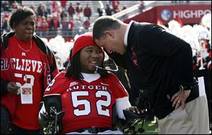 Paralyzed former Rutgers football player Eric LeGrand, center, is greeted by coach Greg Schiano, right, before a Nov. 19, 2011, football game against Cincinnati in Piscataway, N.J. Eric's mother, Karen LeGrand, looks on at left.