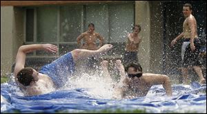 Bowling Green State University Pi Kappa Alpha members Al Glicken of Cleveland left, and Findlay resident Clayton Zaslavsky cool down by slipping and sliding outside of their fraternity house in Bowling Green.