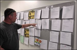 Tom Holloway looks for work at a sign board at JobTrain, an employment center in Menlo Park, Calif.