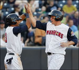 Toledo Mud Hens players Eric Patterson (3) and Jeff Frazier (35) celebrate scoring against  the Pawtucket Red Sox  during the fourth inning.