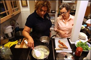 Sevara Cruzat, left, helps her friend Claudia Peyto make dinner for both at Peyton's apartment in Chicago. Peyton is recovering from breast cancer, and Cruzat is one of many friends that pitches in to help Peyton.