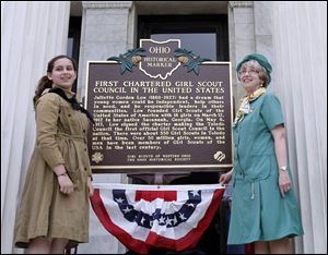 Jennell Polcwiartek, left, and Beverly Miner, in vintage uniforms, pause at the historical marker after its unveiling Saturday on the steps of the museum.