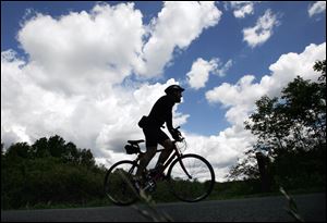 A bicyclist appears to be racing the clouds as he rides through Wildwood Preserve Metropark in West Toledo