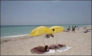 A sun bather lies under umbrellas on Miami Beach, Fla.