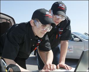 Whitmer High School seniors Josiah Meiring, left, and Mike Stockdale II consult an online serice manual while diagnosing trouble with a new Ford Fusion during the Ford-AAA Auto Skills State Competition.