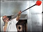  Leonard Marty, master instructor of glass at the Toledo Museum of Art, blows out a glass bulb during a demonstration at the museum's Glass Pavilion. The studio glass movement got its start 50 years ago at the museum.