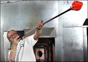 Leonard Marty, master instructor of glass at the Toledo Museum of Art, blows out a glass bulb during a demonstration at the museum's Glass Pavilion. The studio glass movement got its start 50 years ago at the museum.