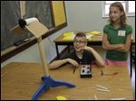  Monroe Zell and Miranda Walker, Harvard Elementary School sixth graders, observe how a change in blade angle affects the speed of their miniature wind turbine. They built it at Monday's summit.