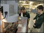  Aaron Magdich, left, and Matt Empie, students at the Toledo Technology Academy, work on their robotic arm in a lab at the school. The academy's robotics team and its hardware are featured as drawing cards to attract eighth graders to enroll.