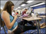  High schooler Brooke Decker plays a game on her phone while listening to her iPod.