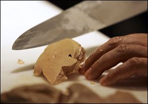 A chef prepares to slice a portion of foie gras, a fatty duck
liver delicacy.