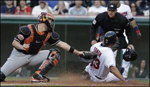 Cleveland Indians' Johnny Damon is safe at home, beating the tag by Miami Marlins catcher John Buck in the second inning of an interleague baseball game in Cleveland on Friday.