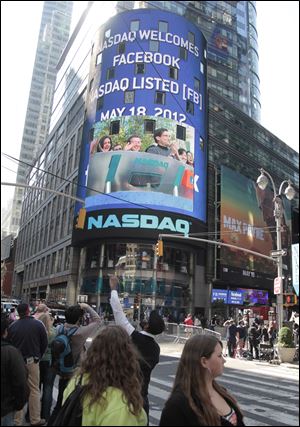 People in New York's Times Square watch Nasdaq's giant monitor as Facebook's stock begins trading on the Nasdaq stock market in New York.