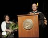  Linda Helmer listens as her husband, outgoing President Robert Helmer, addresses the graduates. He was honored at the ceremony for his service to the university and its values. 