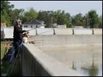 Dan Engel of Cincinnati uses a stepladder to fish at a wall along the Sandusky River in downtown Fremont.
