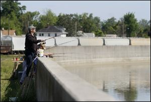 Dan Engel of Cincinnati uses a stepladder to fish at a wall along the Sandusky River in downtown Fremont.